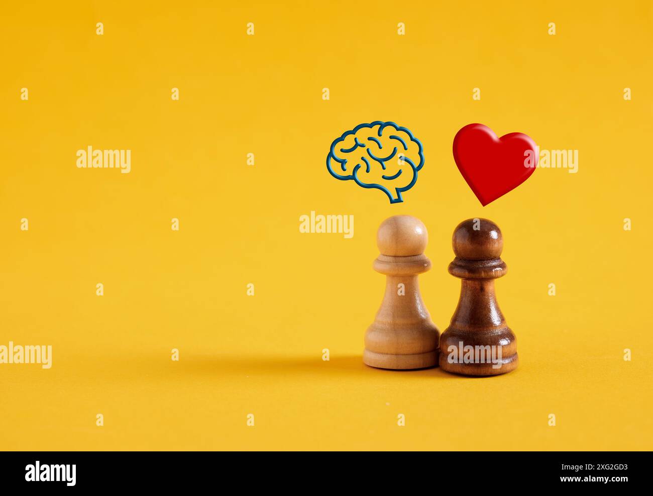 Logica e concetto di emozione. Pensiero razionale o emotivo o processo decisionale. Pedine da scacchi con simboli umani del cervello e del cuore su sfondo giallo. Foto Stock