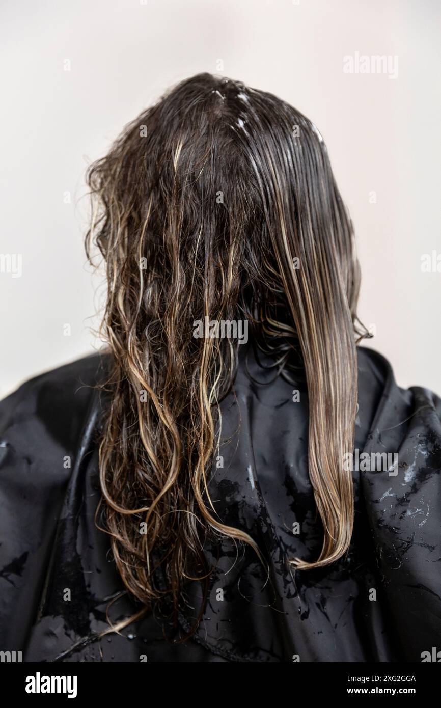 Donna con capelli ricci castani che riceve una delizia dal parrucchiere. Stile di vita Foto Stock