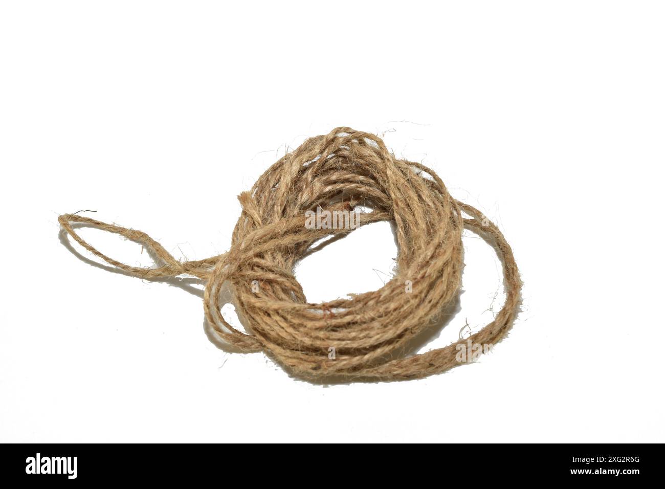 Uno spiedino di spago realizzato con fibre naturali giace su uno sfondo bianco. Foto Stock