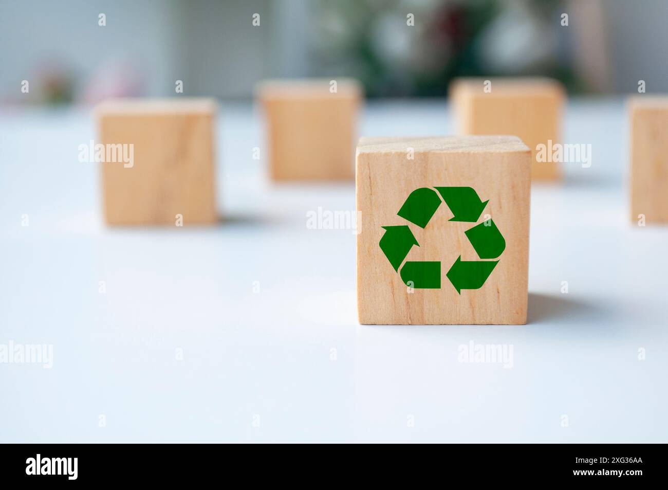 Riciclare il simbolo su un cubo di legno con sfondo sfocato. Concetto di riciclaggio. Foto Stock