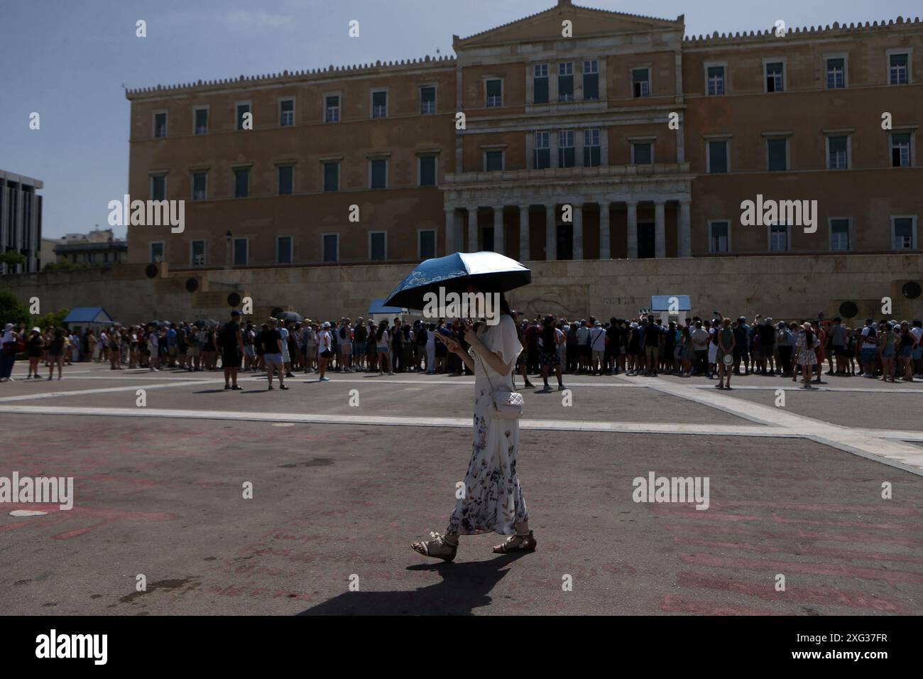 Un turista tiene un ombrello di fronte al Monumento al Milite Ignoto in Piazza Syntagma durante un'ondata di caldo, ad Atene. L'estesa area ad alta pressione sulle coste dell'Africa e del Mediterraneo centrale, accompagnata da masse d'aria molto calde, si sta gradualmente estendendo verso est e porterà temperature molto elevate in Grecia dall'11 al 14 giugno. Foto Stock