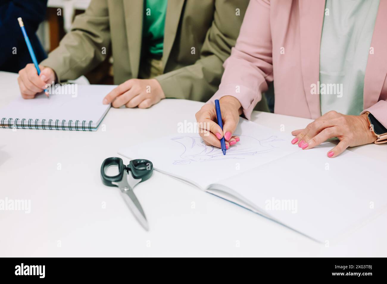 Stilista di moda che disegna abiti eleganti nel loro atelier Foto Stock