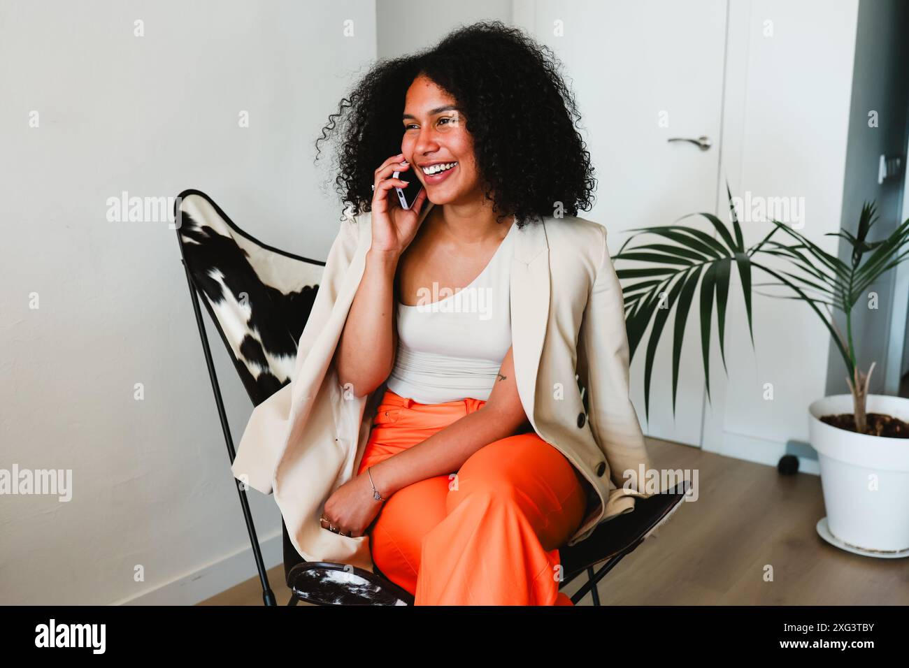 Donna latina africana in una telefonata, sorridente a casa Foto Stock