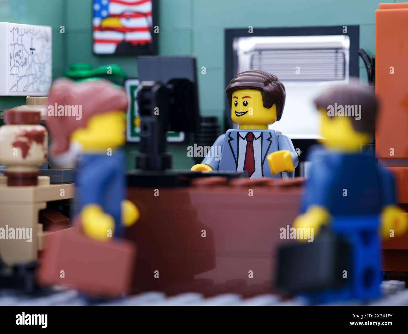 Tambov, Federazione Russa - 02 luglio 2024 Una minifigura d'affari Lego che lavora dietro un computer mentre altri due uomini d'affari hanno una conversazione Foto Stock