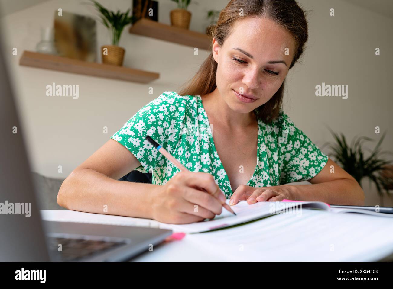 Formazione continua. Studentessa adulta che studia a casa, scrive esercizi nel libro degli esercizi. Foto Stock