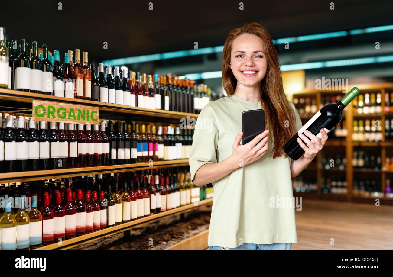 Donna bruna che indossa una t-shirt casual che acquista vino biologico in un negozio di liquori. Foto Stock