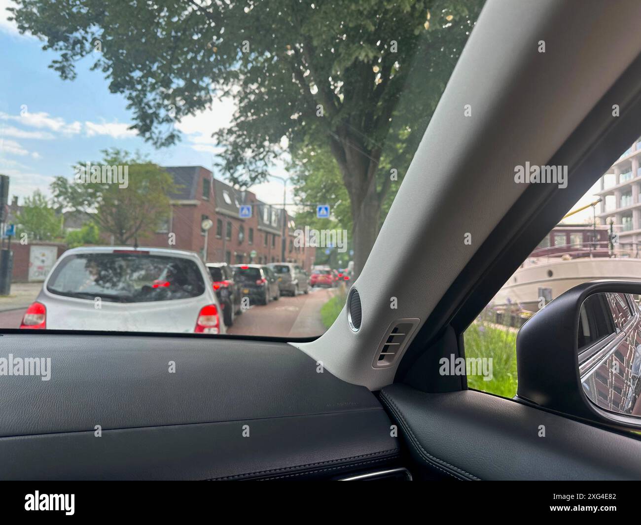 Auto nel traffico lungo la strada della città, vista dal sedile del conducente Foto Stock