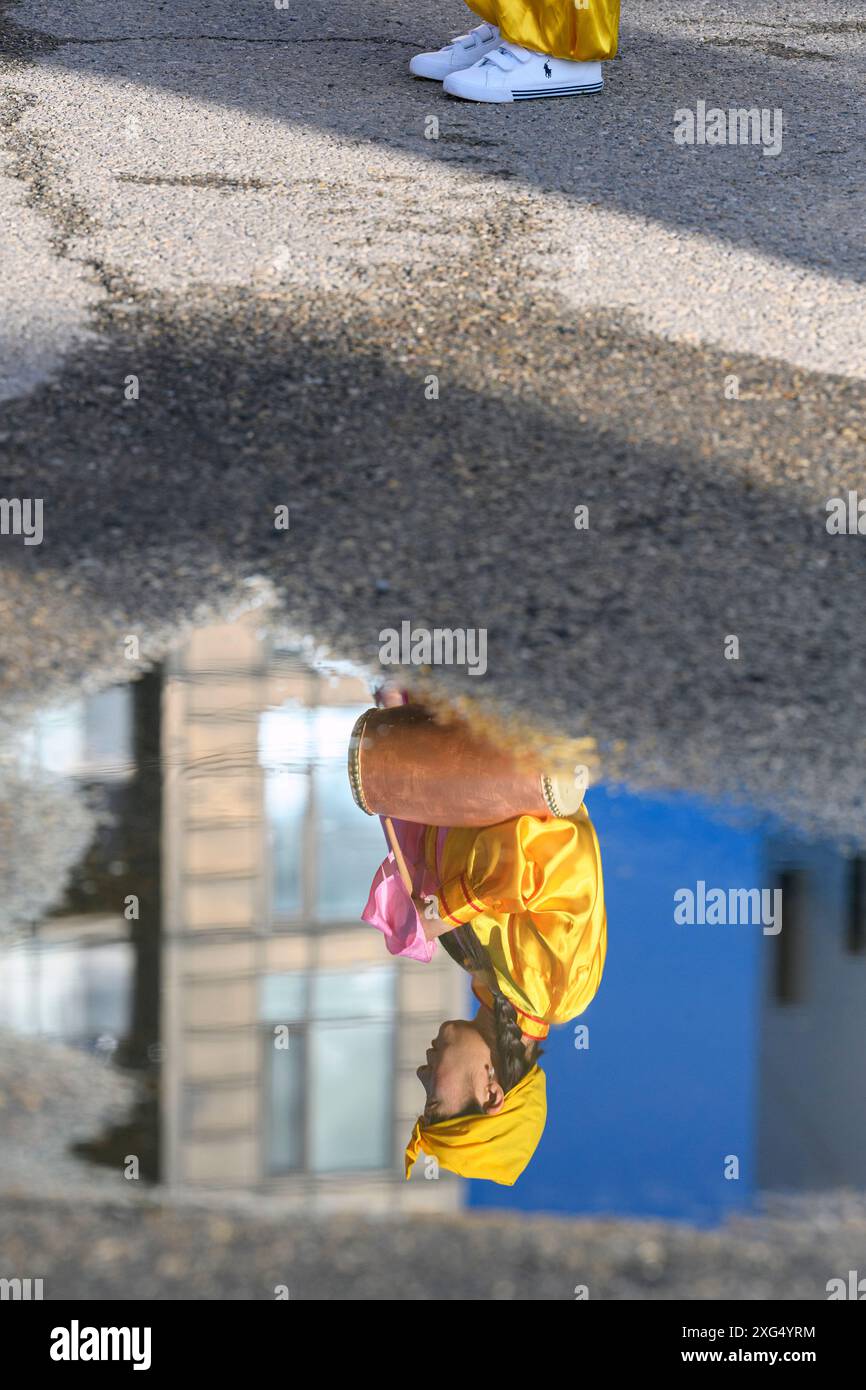 Riflesso in una strada urbana di un batterista dei Falun Gong che suona alla Calgary Stampede Parade Foto Stock