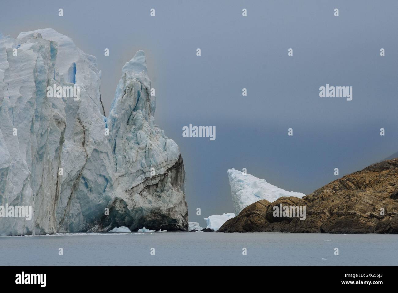 Bellissimo ghiacciaio che avanza verso la roccia. La lotta dei più forti con i più deboli. Foto Stock
