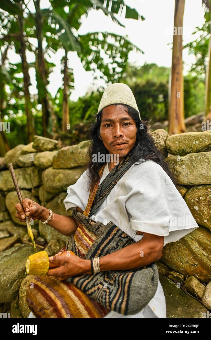 Un Arahuaco Mamo presso la comunità Atikuakumake nella Sierra Nevada de Santa Marta trasuda saggezza e serenità, incarnando la leadership spirituale e il patrimonio culturale del popolo Arahuaco. Porta un poporo, un gourd tradizionale usato per scopi spirituali e sociali, che simboleggia la sua profonda connessione con le tradizioni ancestrali. Foto Stock