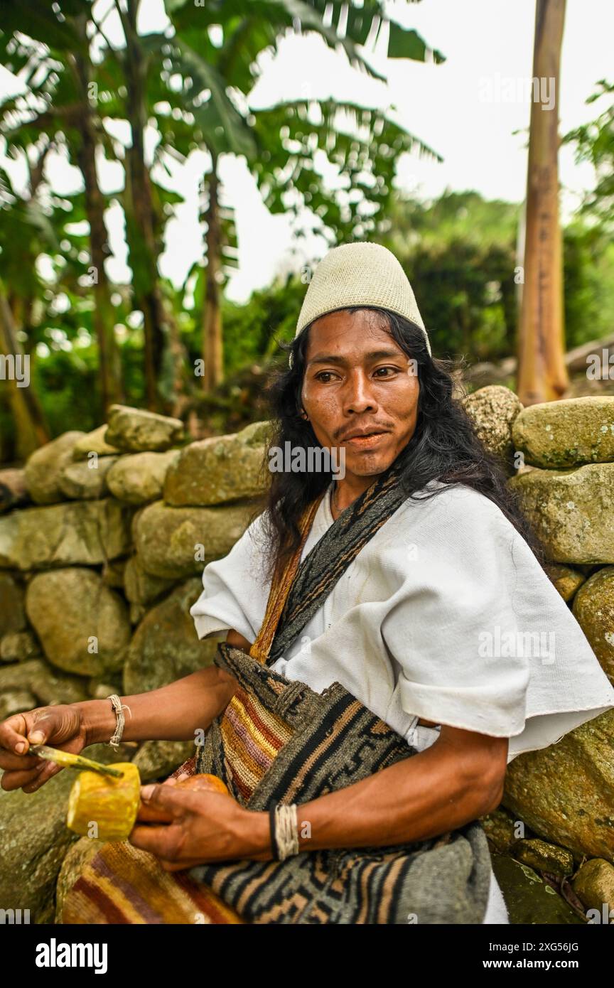 Un Arahuaco Mamo presso la comunità Atikuakumake nella Sierra Nevada de Santa Marta trasuda saggezza e serenità, incarnando la leadership spirituale e il patrimonio culturale del popolo Arahuaco. Porta un poporo, un gourd tradizionale usato per scopi spirituali e sociali, che simboleggia la sua profonda connessione con le tradizioni ancestrali. Foto Stock