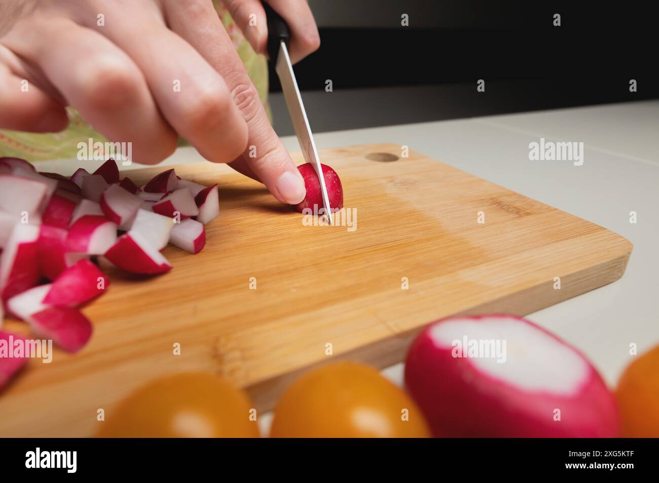 Le mani femminili tengono un ravanello su un tabellone, primo piano. layout o banner per il sito web culinario Foto Stock