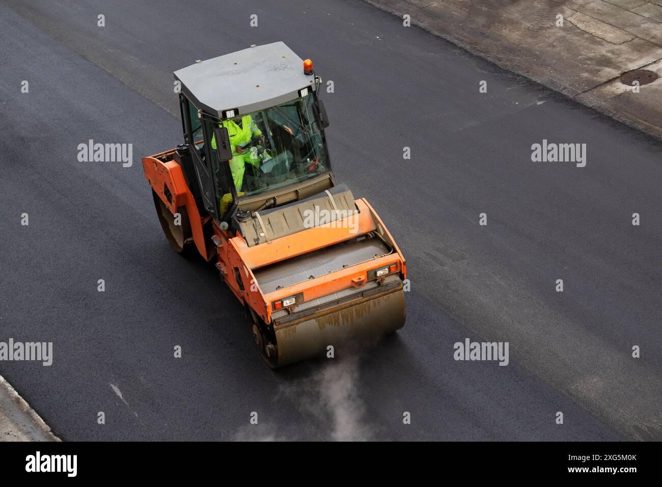 Rullo per asfalto in funzione. Costruzione di nuove strade, riparazione di marciapiedi. Vista ad angolo alto Foto Stock