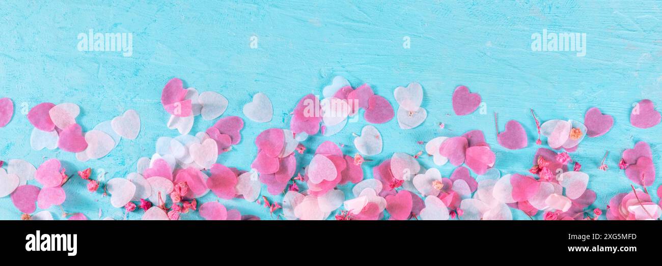 Panorama di San Valentino o di nozze con cuori rosa e fiori di confetti, un banner panoramico piatto e posato su sfondo blu con un posto per il testo Foto Stock