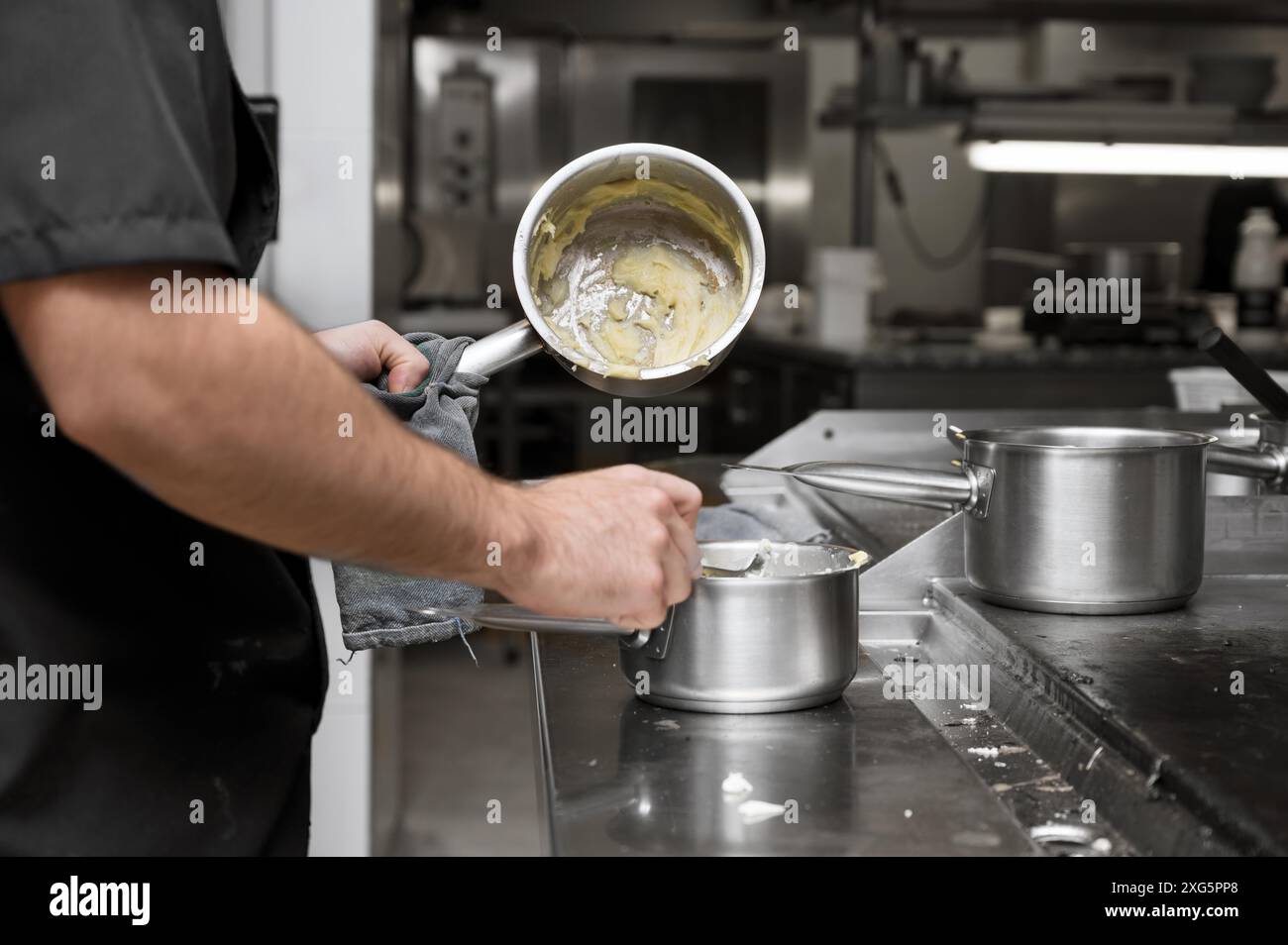 Salsa di agitazione chef in pentola di acciaio inossidabile, primo piano. Cucina professionale, ristorante. Foto di alta qualità Foto Stock