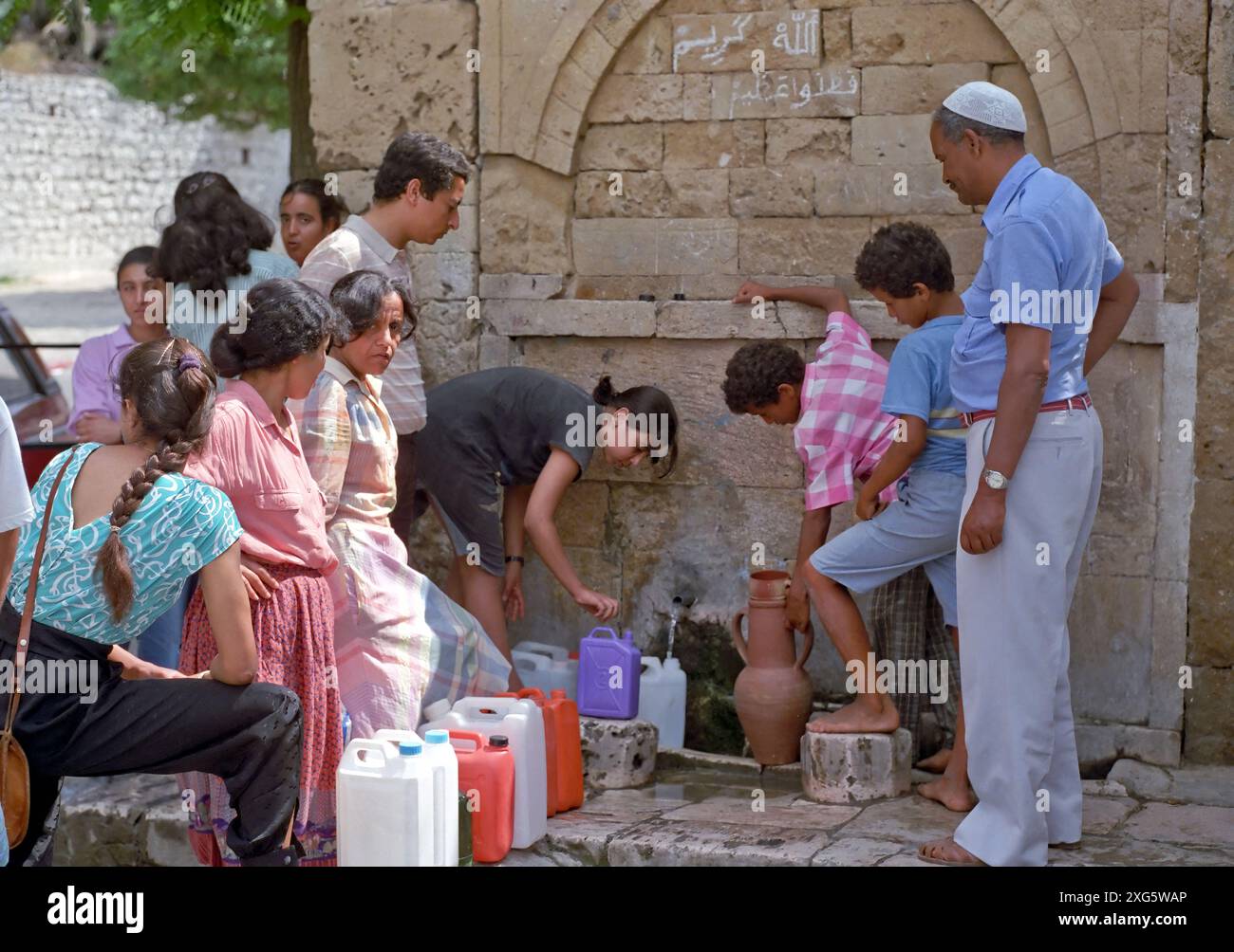 Tunisia, ha detto Sidi Bou. Alla fontana. Gli abitanti del villaggio raccolgono l'acqua che si ritiene abbia proprietà curative speciali. "Allah Kareem" ("Dio è generoso") è scritto sulla pietra sopra il rubinetto dell'acqua. Foto Stock