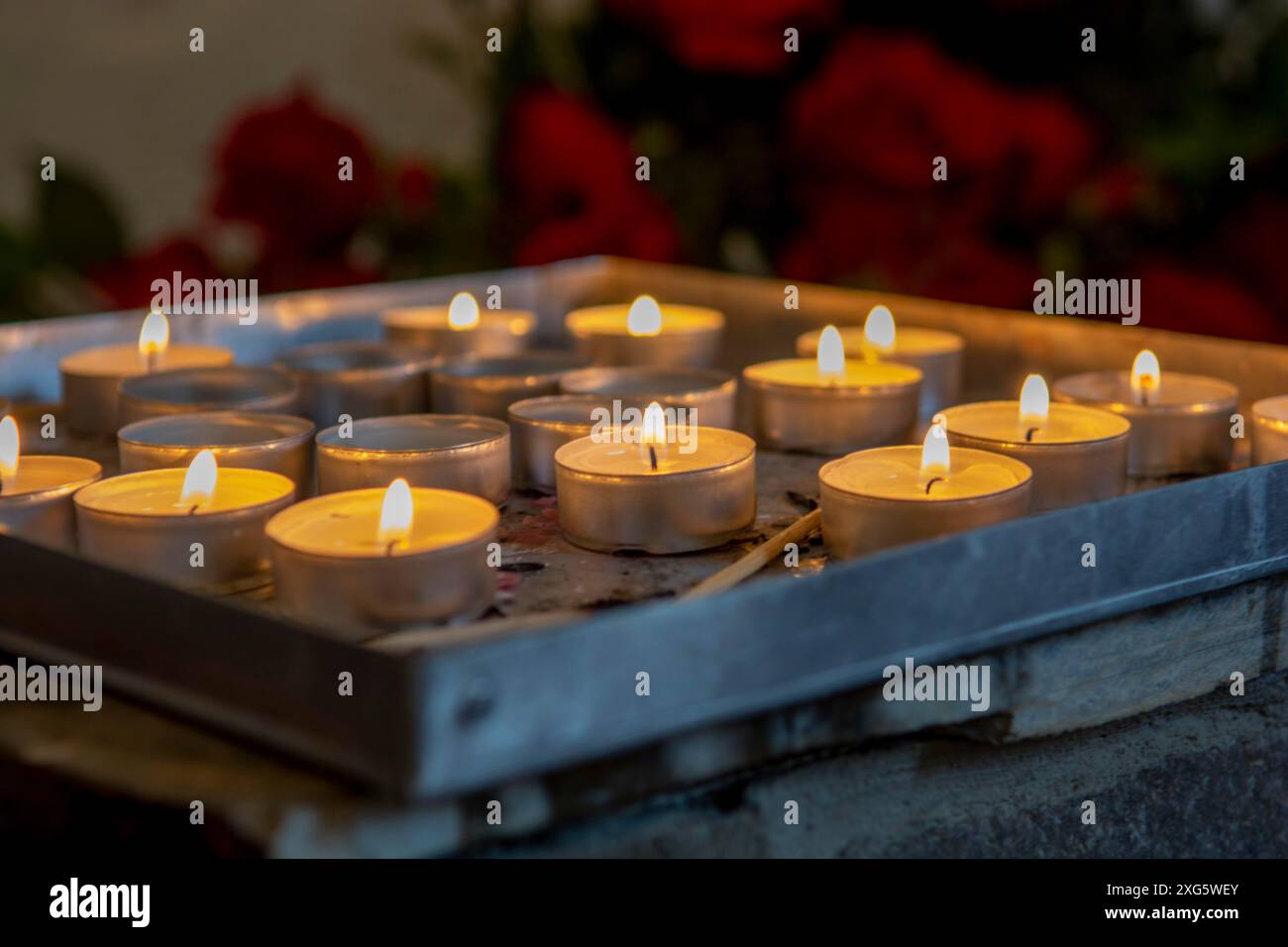 Bruciare candele di preghiera all'interno di una chiesa cattolica. Luci del tè accese. Messa a fuoco selettiva Foto Stock