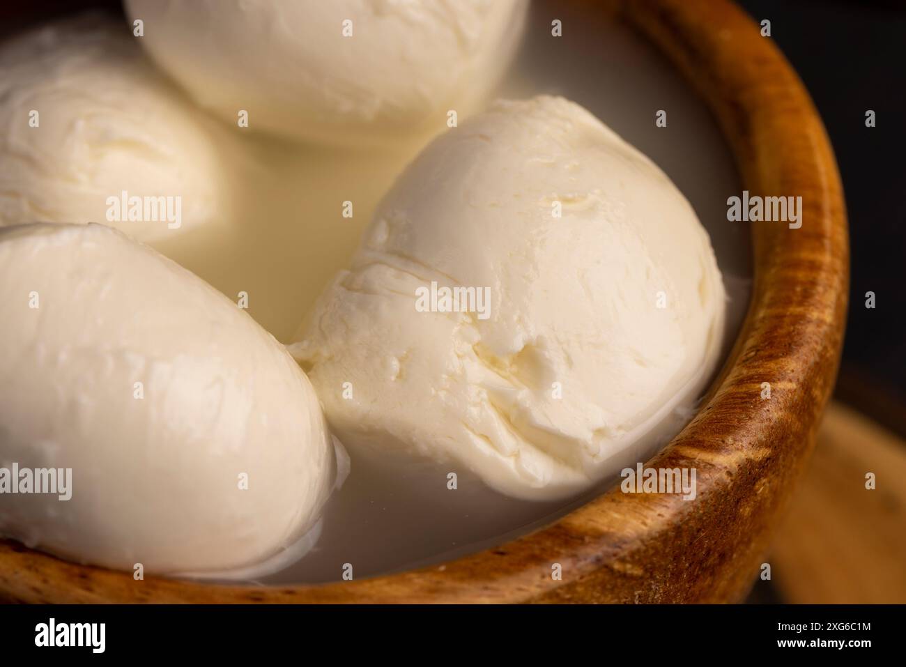 polpette di formaggio bianco in una ciotola di legno, latte e formaggio morbido in salamoia Foto Stock