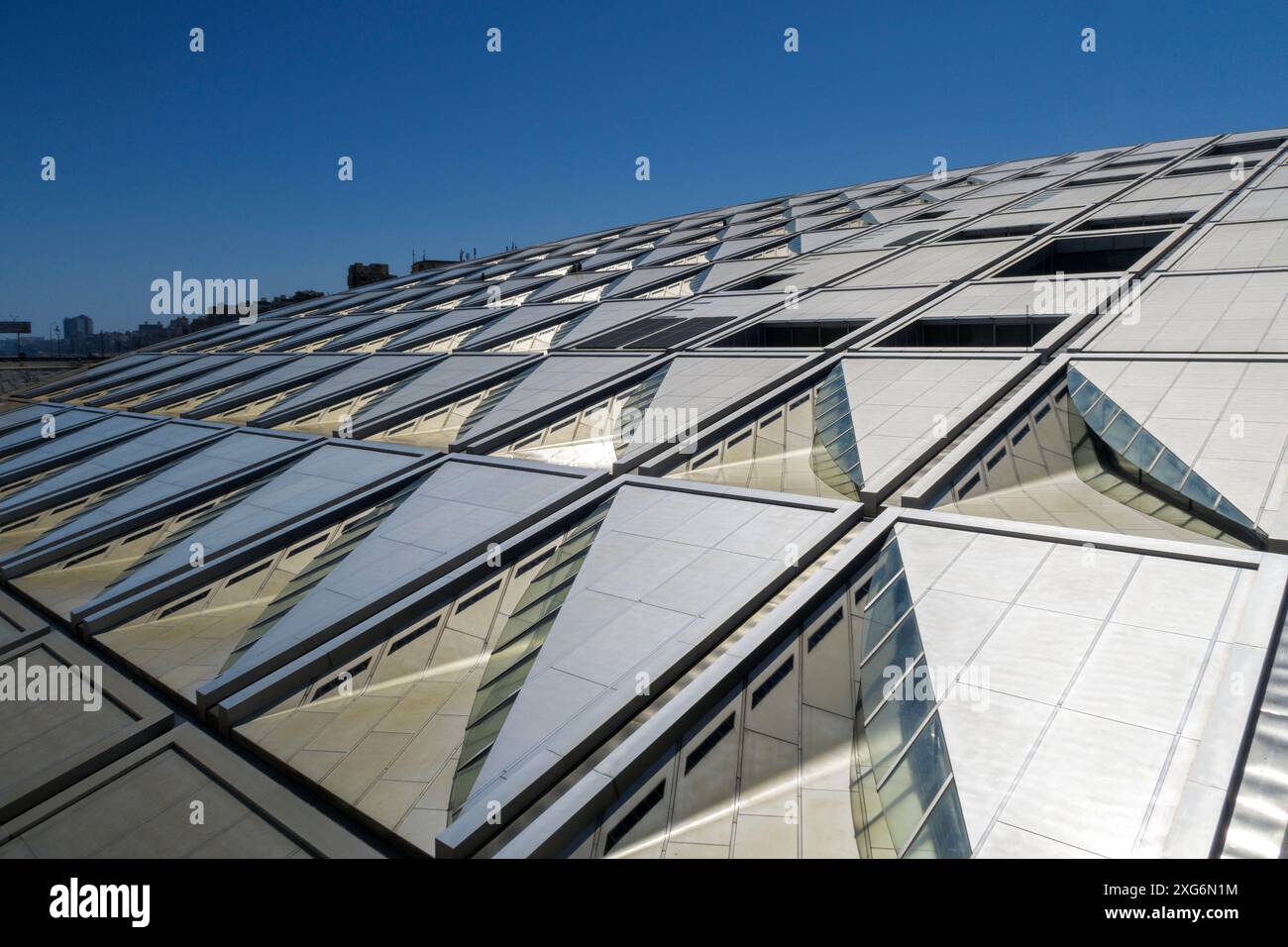 Moderno dettaglio architettonico di una struttura geometrica del tetto in vetro e metallo che riflette la luce del sole sotto un cielo azzurro cristallino presso la biblioteca di Alessandria, Egitto Foto Stock