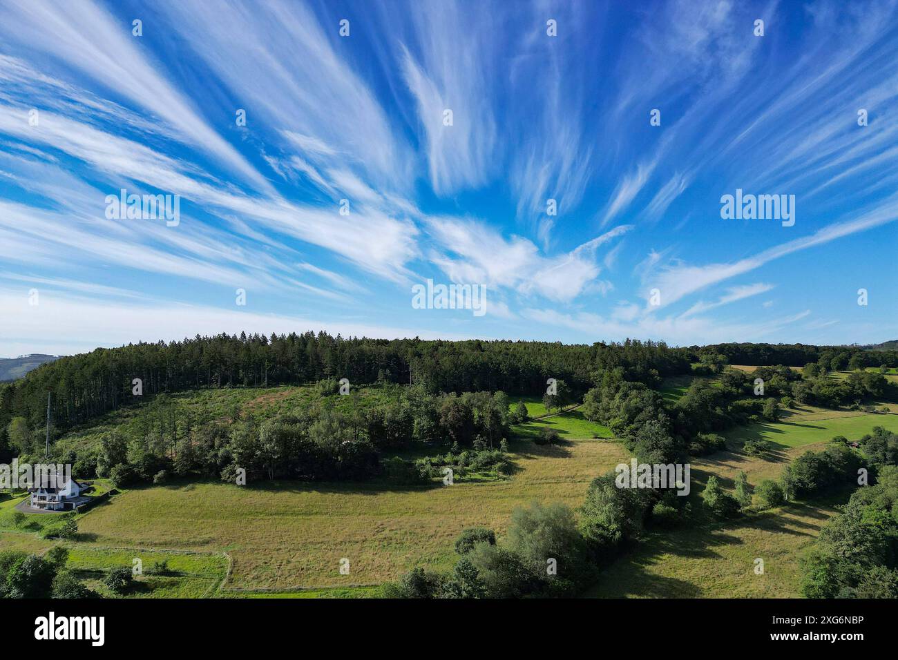 Ein schoener Schöner Sommermorgen im Siegerland. Luftaufnahme der Natur Rund um den Ort Siegen-Oberschelden. Der Himmel ist blau mit leichter Bewoelkung Bewölkung, Cirruswolken. AM Bildrand collega steht ein einzelnes Haus. Sommer im Siegerland AM 07.07.2024 a Siegen/Deutschland. *** Una bella mattinata d'estate a Siegerland Vista aerea della natura intorno al villaggio di Siegen Oberschelden il cielo è blu con nuvole chiare, nuvole di cirrus al bordo dell'immagine a sinistra è una casa singola Estate a Siegerland il 07 07 2024 a Siegen Germania Foto Stock