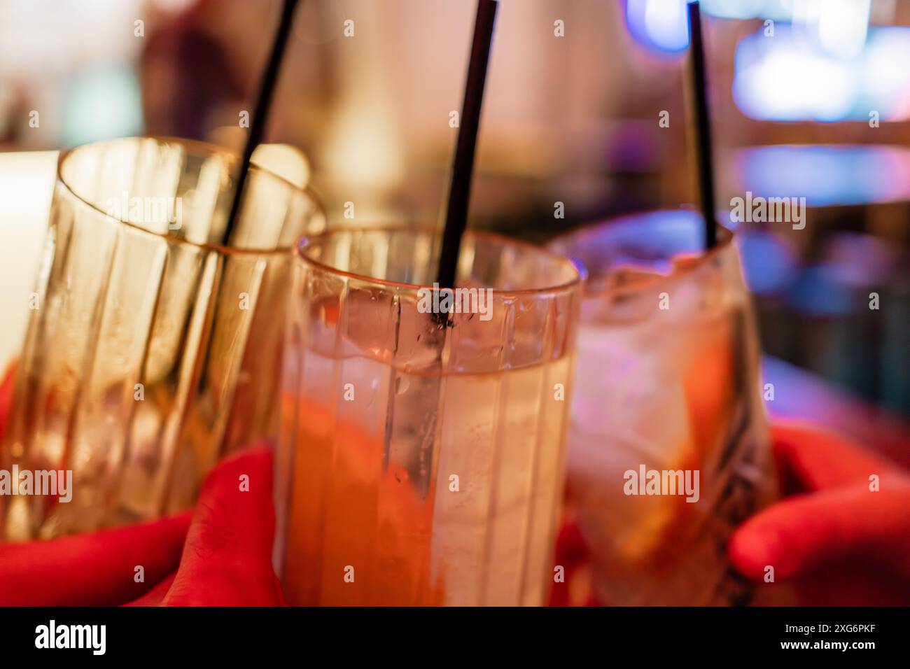 Primo piano di tre persone che sorseggiano cocktail al bar, drink e cocktail con spazio per testo Foto Stock