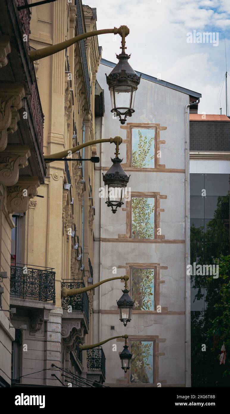 Scoprite il vibrante mix di arte e storia a Lione, dove uno splendido murale incontra un edificio storico splendidamente adornato con incantevoli lanterne. Foto Stock