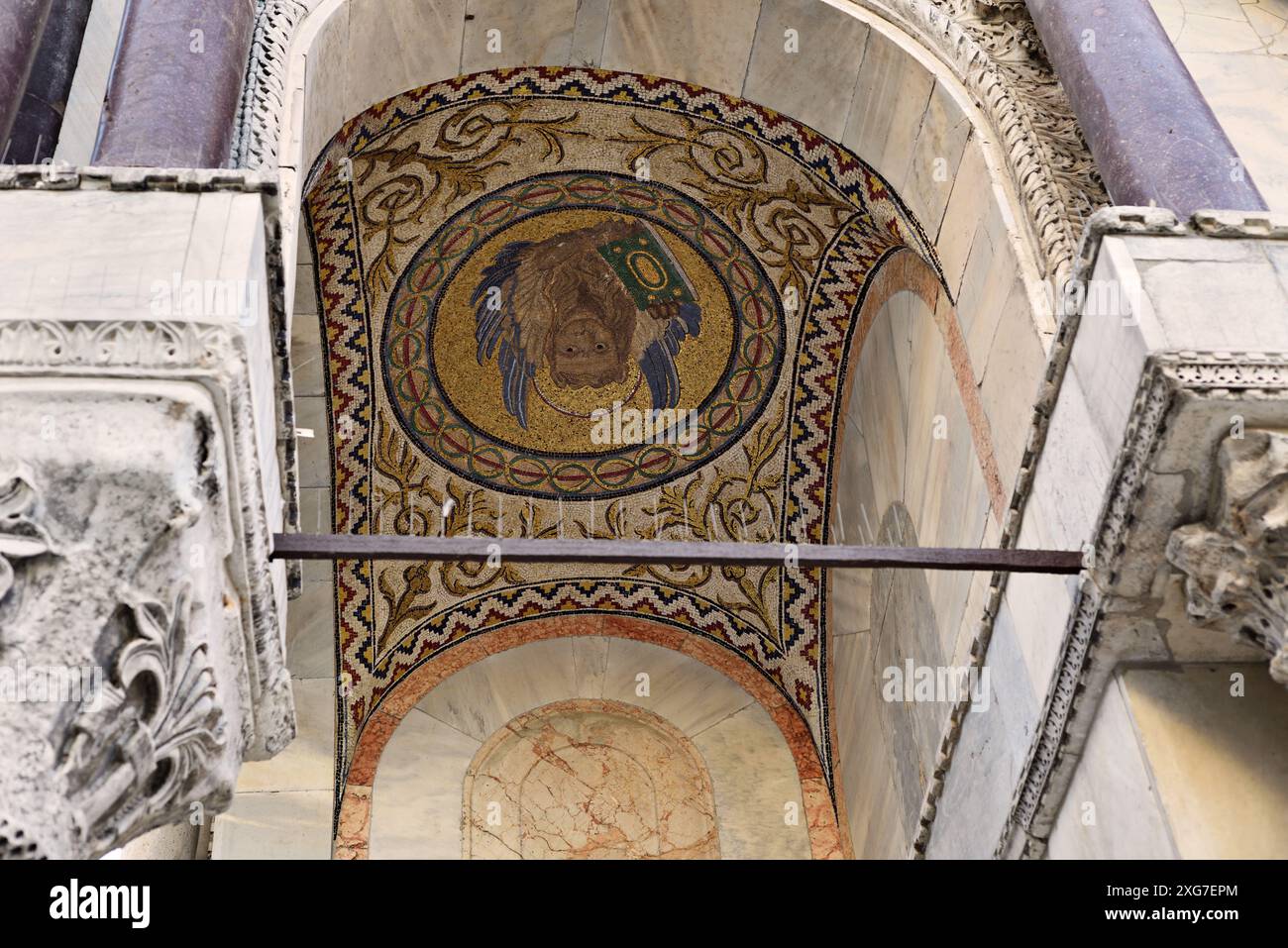 Dettagli dalla facciata della basilica di San Marco, mosaico del leone alato di San Marco con un libro, colonne rosse, capitelli intagliati Foto Stock