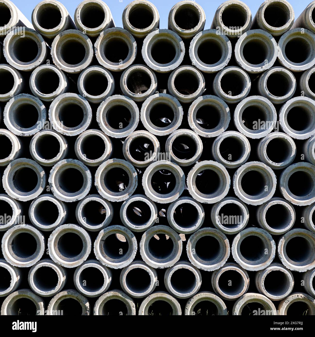 Tubi in calcestruzzo impilati su terreni dell'impianto. Foto Stock