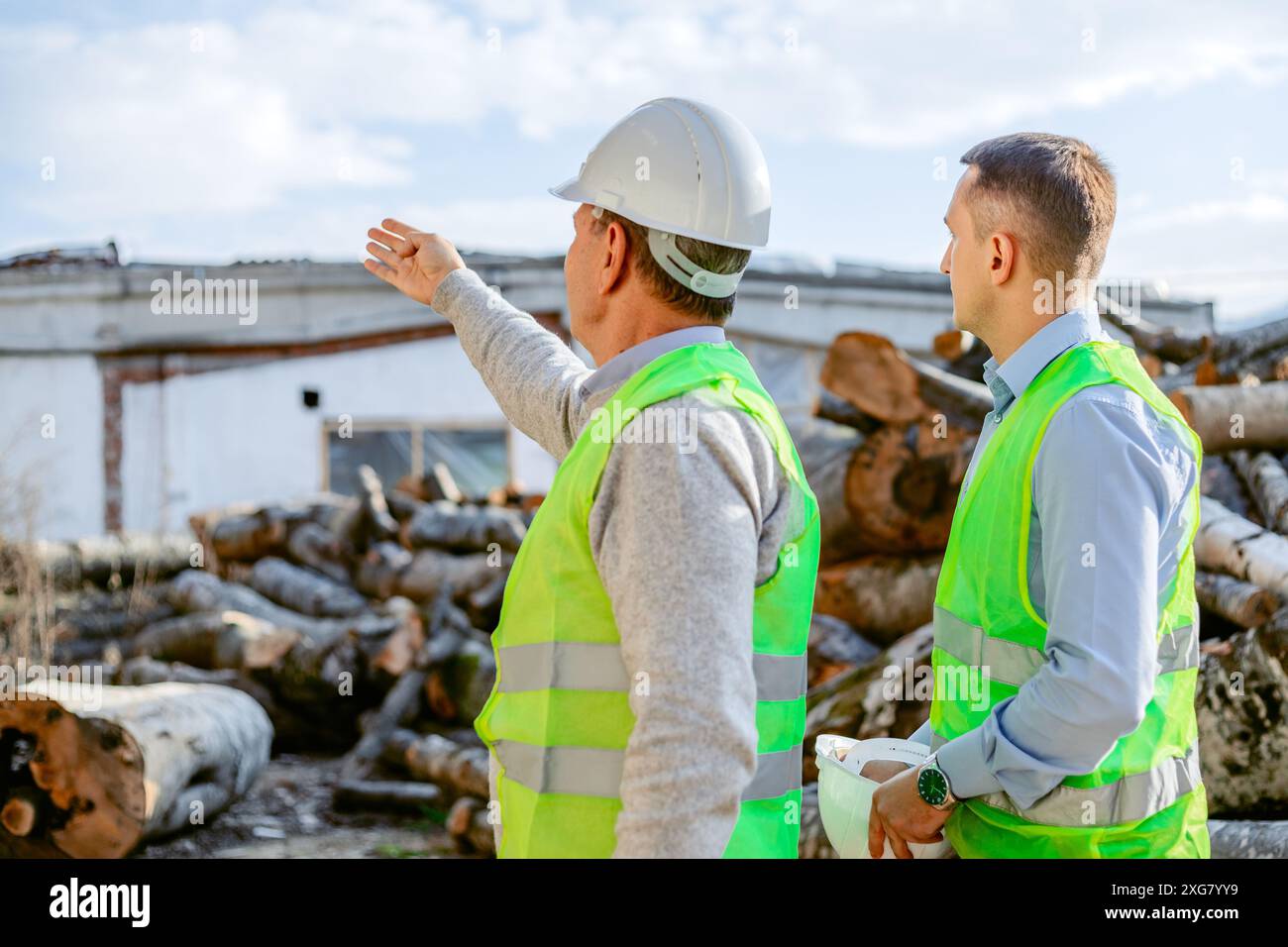 Due operai edili che indossano giubbotti di sicurezza stanno discutendo di un cantiere. Foto Stock