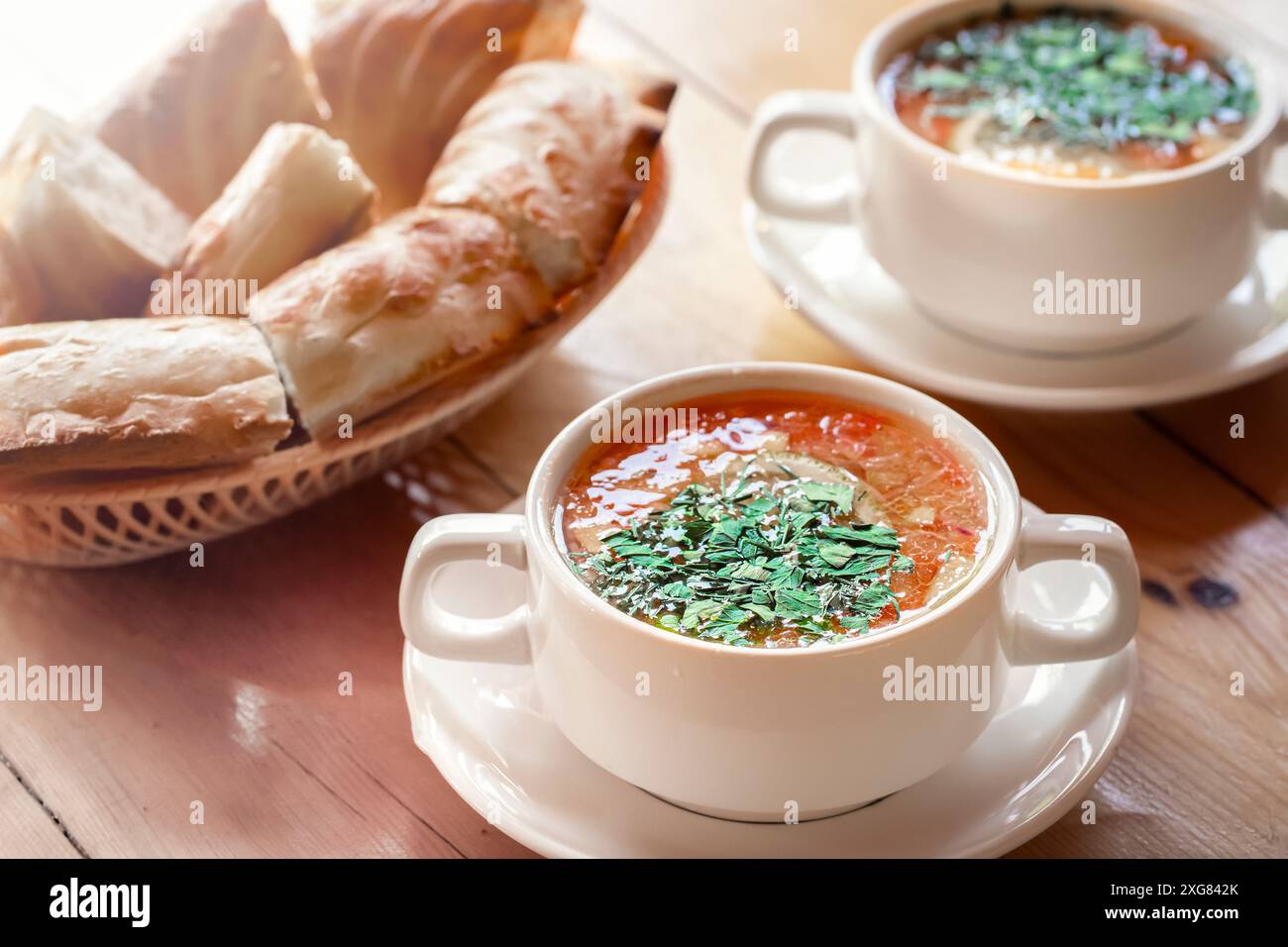 Concediti un pasto delizioso con due porzioni di zuppa alle erbe aromatiche, accompagnate da pane fresco, per un'esperienza culinaria accogliente Foto Stock