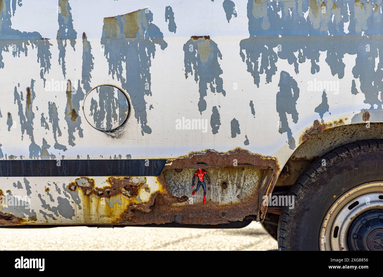 un piccolo uomo ragno che nasconde la sezione arrugginita di un vecchio furgone schivato Foto Stock