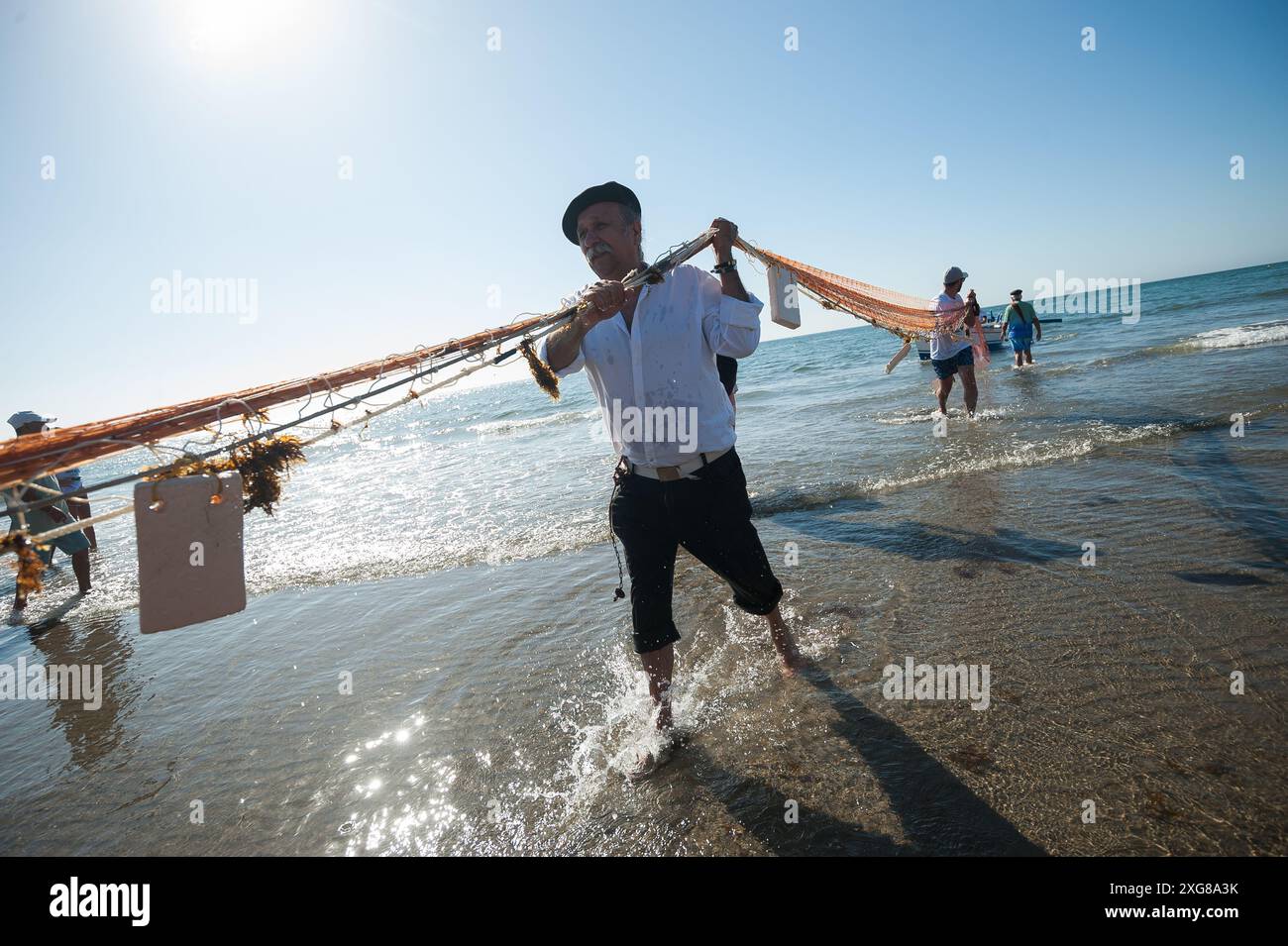 Si vede un uomo che porta una grande rete sulla spiaggia mentre partecipa alla mostra "la Tirada del Copo" alla spiaggia di Los Boliches. Ogni anno a Fuengirola, la gente del posto celebra un'antica tradizione di pesca conosciuta come "la Tirada del Copo" per mostrare le abilità e il commercio di marinai e pescatori durante la cattura dei pesci in mare. Come dice la tradizione, durante la "Tirada del Copo", i marinai gettano le reti in mare, formando un semicerchio, mentre altri tirano le reti verso la spiaggia per catturare tutti i pesci. La pratica della tirada del copo è attualmente vietata. (Foto di Jesus Merida/SOPA Images/S Foto Stock