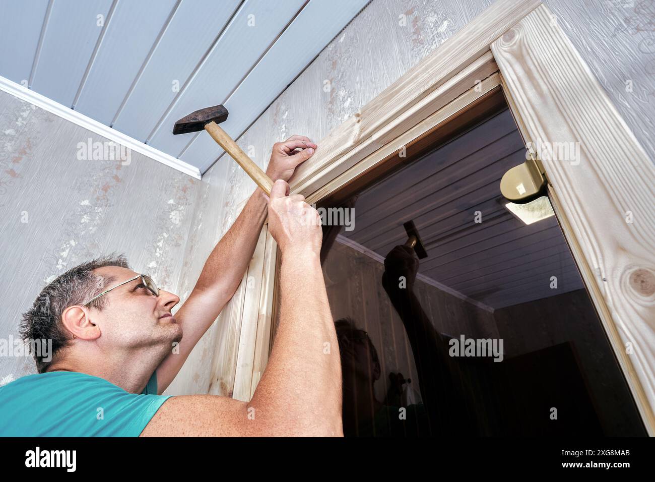 Utilizzare un martello per chiodi per fissare l'involucro ai rivestimenti delle portiere. Foto Stock