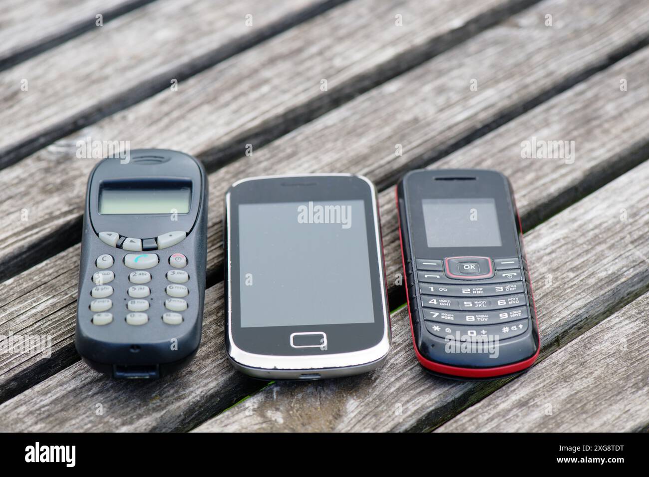 Vecchi telefoni cellulari su un vecchio tavolo di legno intemprato Foto Stock