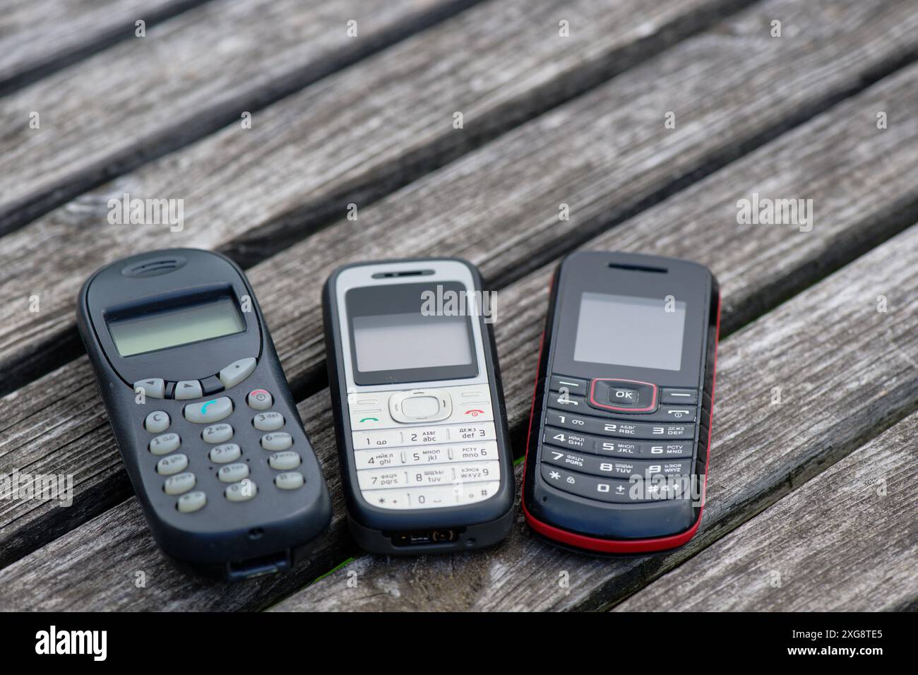 Vecchi telefoni cellulari su un vecchio tavolo di legno intemprato Foto Stock