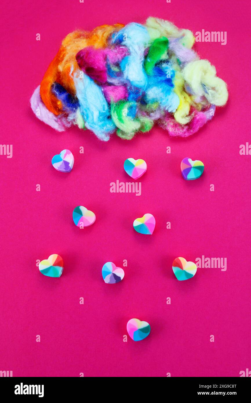 Pioggia di cuori che cadono da una nuvola multicolore Foto Stock