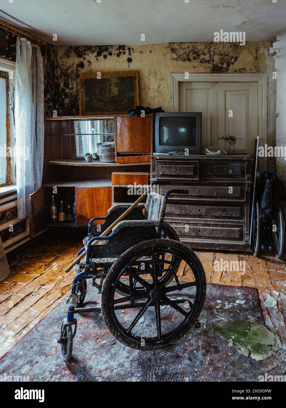 Sedia a rotelle vuota in una vecchia casa abbandonata. Foto Stock