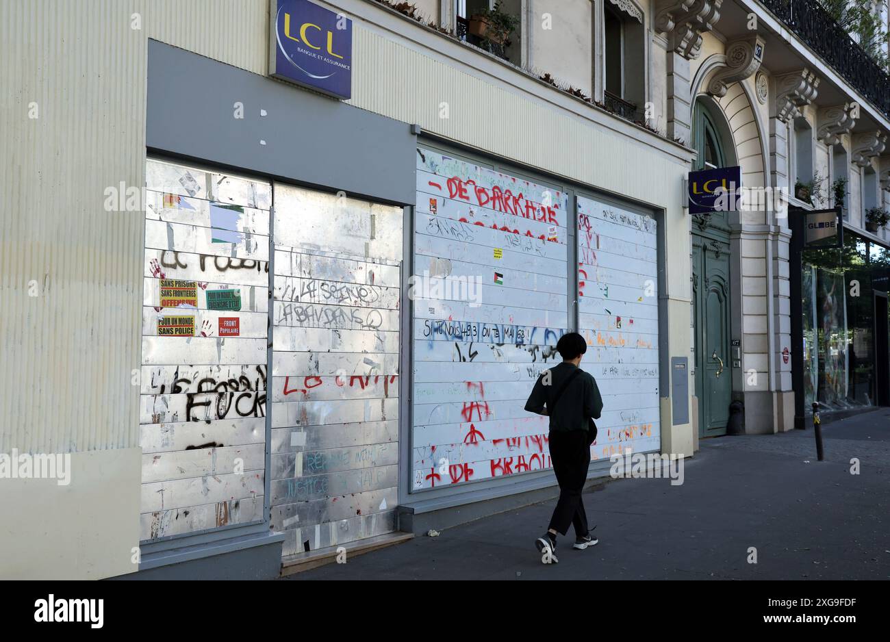 Parigi, Francia. 7 luglio 2024. Una donna cammina davanti a una banca barricata per paura di danni da parte dei manifestanti mentre i cittadini francesi votano durante il turno finale delle elezioni parlamentari SNAP a Parigi, in Francia, domenica 7 luglio 2024. Le elezioni hanno gettato un parlamento impiccato, con un'alleanza di sinistra che ha inaspettatamente conquistato il primo posto davanti all'estrema destra, lasciando i partiti politici francesi di fronte all'arduo compito di formare un governo. Foto di Maya Vidon-White/UPI credito: UPI/Alamy Live News Foto Stock