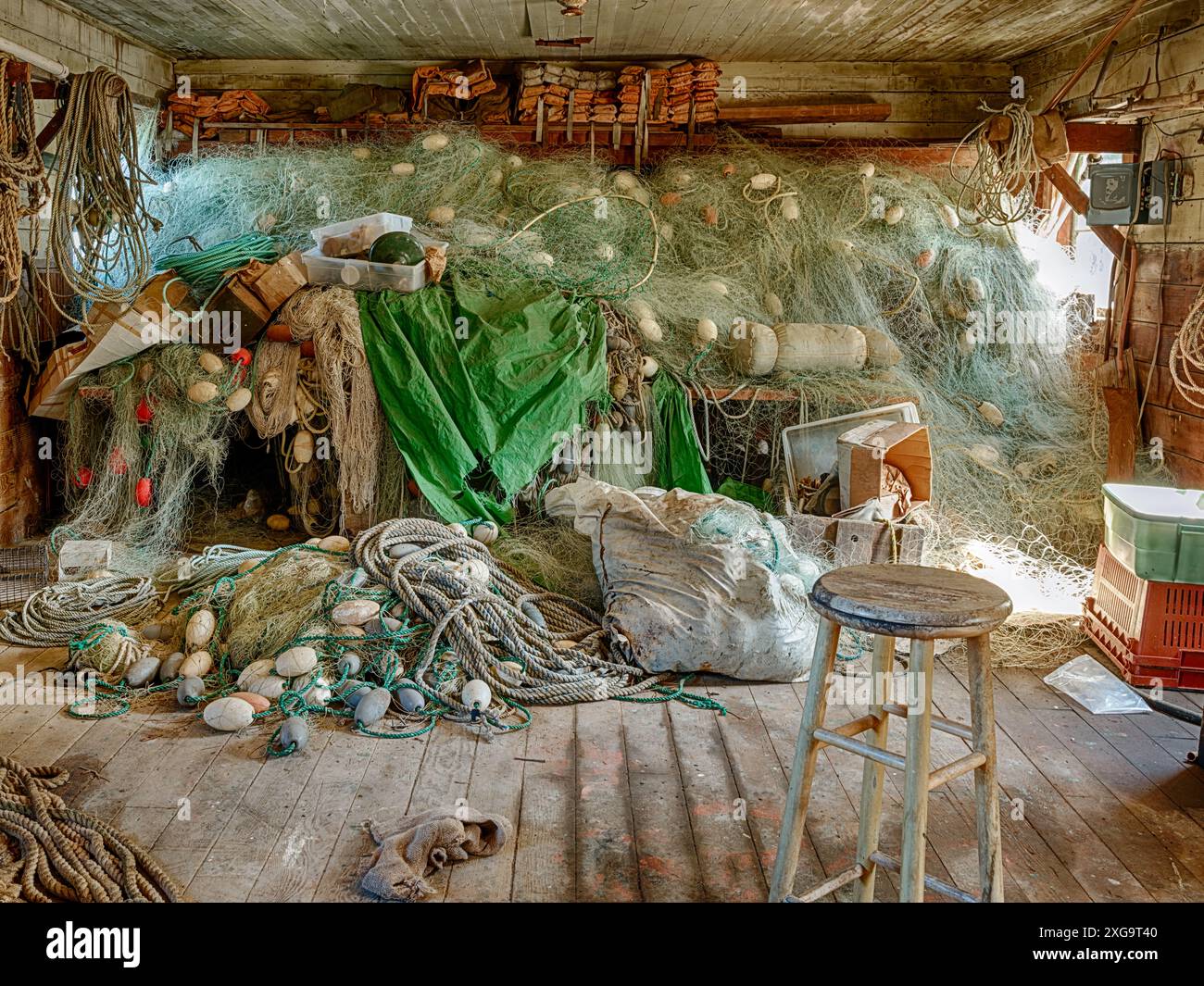 Le reti da pesca sono accumulate sul pavimento accanto a un muro nel capannone di una fattoria di ostriche a Wallowa Bay nello stato di Washington. Foto Stock