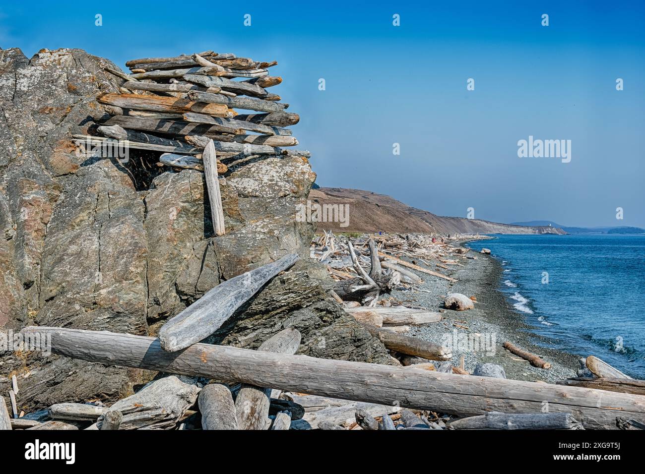 Una struttura a strapiombo costruita da tronchi è arroccata su un affioramento roccioso per guardare su una lunga spiaggia in entrambe le direzioni. Foto Stock