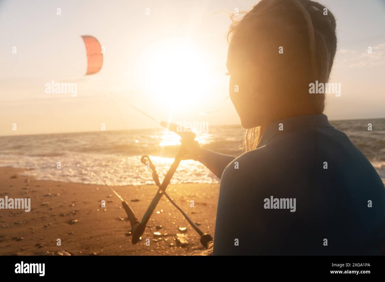La donna sportiva kitesurfer tiene il suo aquilone sulla superficie del mare con le onde al tramonto. Spazio per copiare sport acquatici. Istruttore di kitesurf in cerca Foto Stock