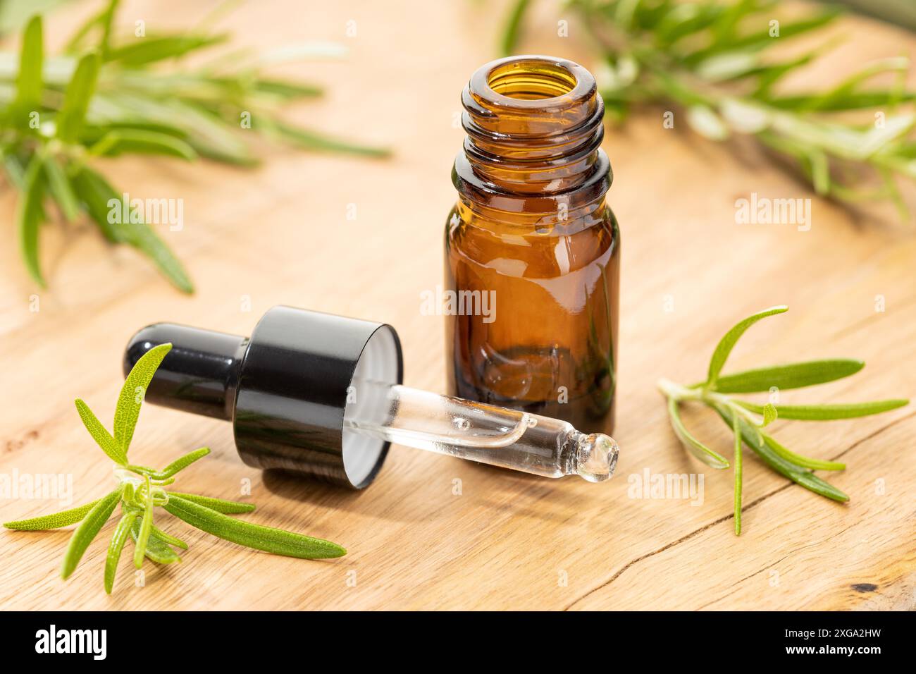 Olio essenziale di rosmarino su tavola di legno ancora vita. Rimedi a base di erbe Foto Stock