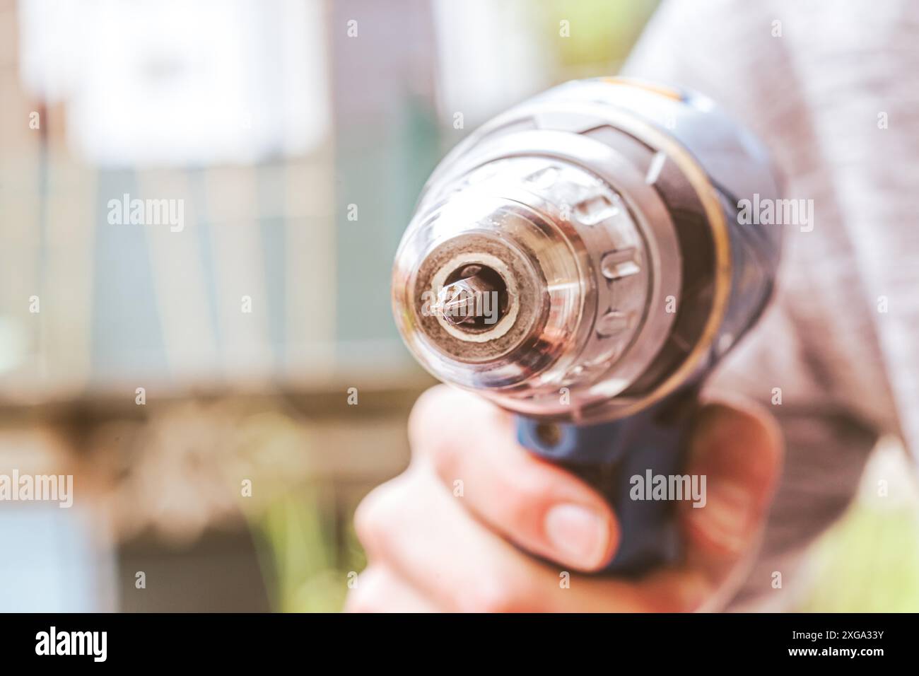Fai da te il manipolo di casa sta tenendo un cacciavite cordless, all'aperto Foto Stock