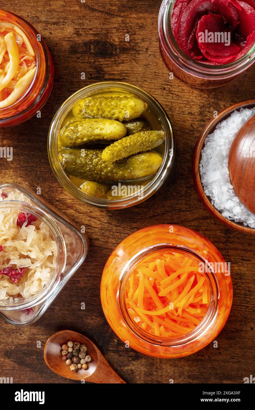 Alimenti probiotici. Cibo fermentato. Crauti, carote, sottaceti e altre conserve in vasetti di vetro. Cucina vegana fatta in casa su un legno rustico scuro Foto Stock