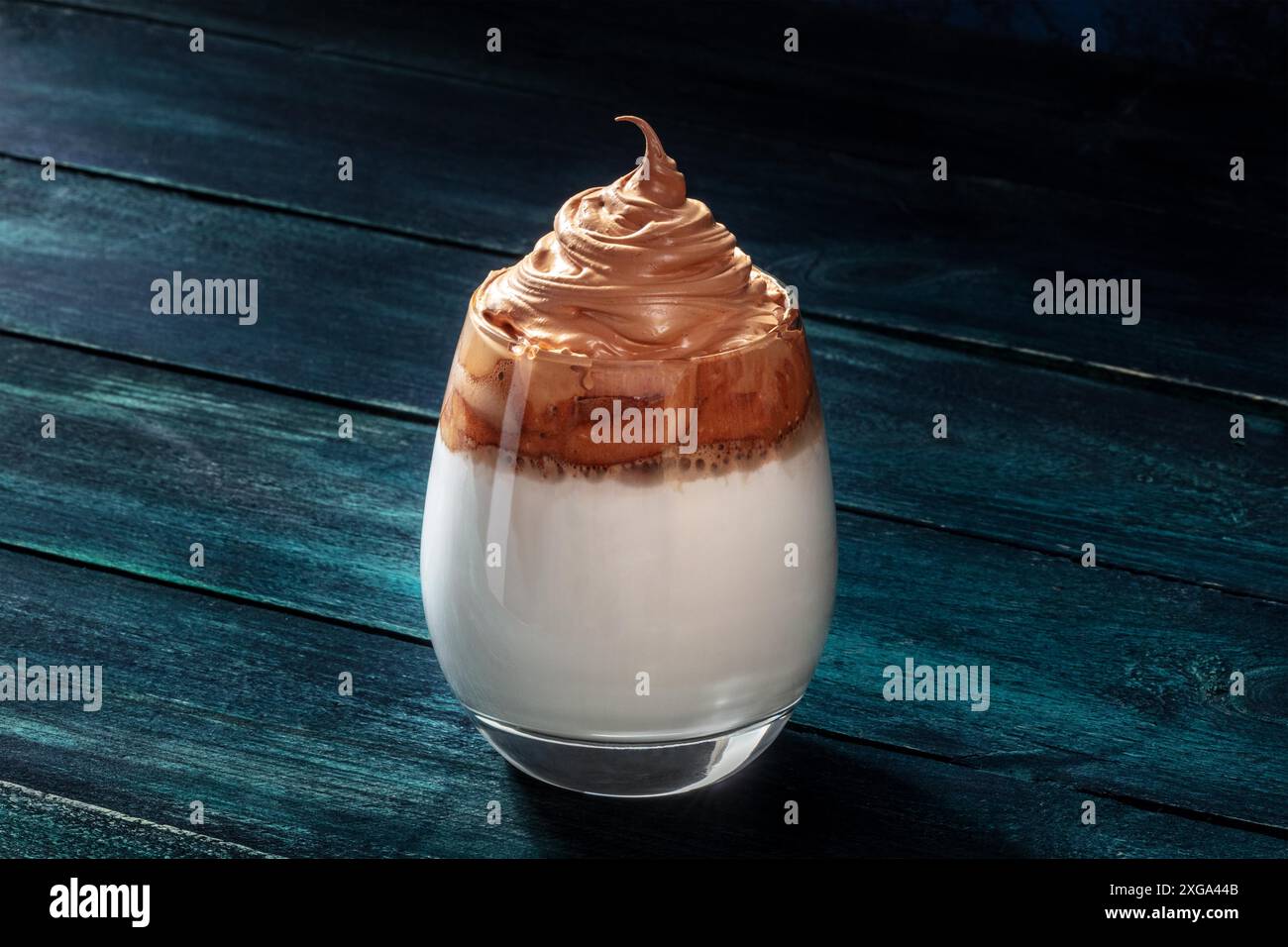 Caffè freddo Dalgona su sfondo blu scuro. Bevanda coreana dolce con caffè istantaneo e crema Foto Stock