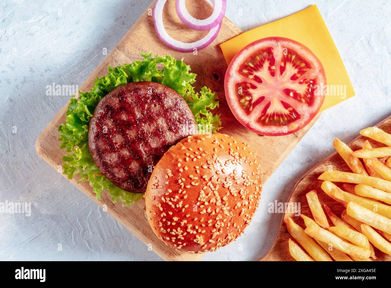 Ingredienti del Burger con patatine fritte. Bistecca di manzo con hamburger e verdure al sesamo, colpo di testa Foto Stock