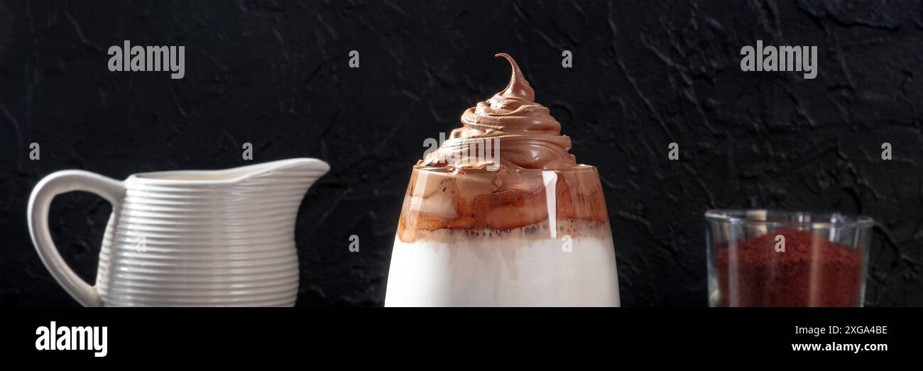 Panorama del caffè freddo Dalgona su sfondo nero. Bevanda frullati coreana con ingredienti Foto Stock