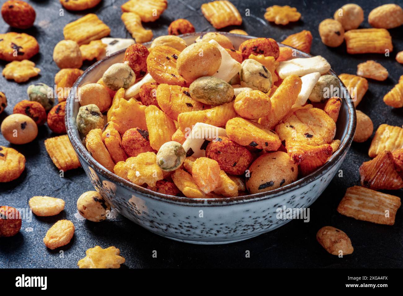 Cracker di riso giapponesi in una ciotola su sfondo nero ardesia, tipico spuntino asiatico Foto Stock