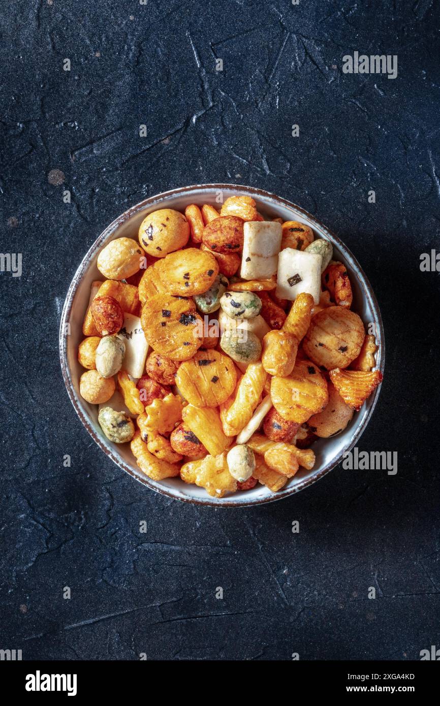 Cracker di riso giapponesi in una ciotola su sfondo nero ardesia, girato dall'alto con un posto per il testo Foto Stock