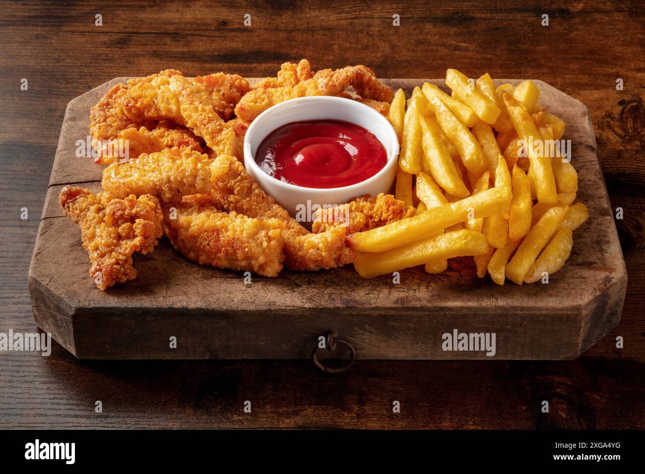 Spicchi di pollo in pastella, nocciole croccanti, con una salsa barbecue su un tavolo di legno, fast food americano Foto Stock